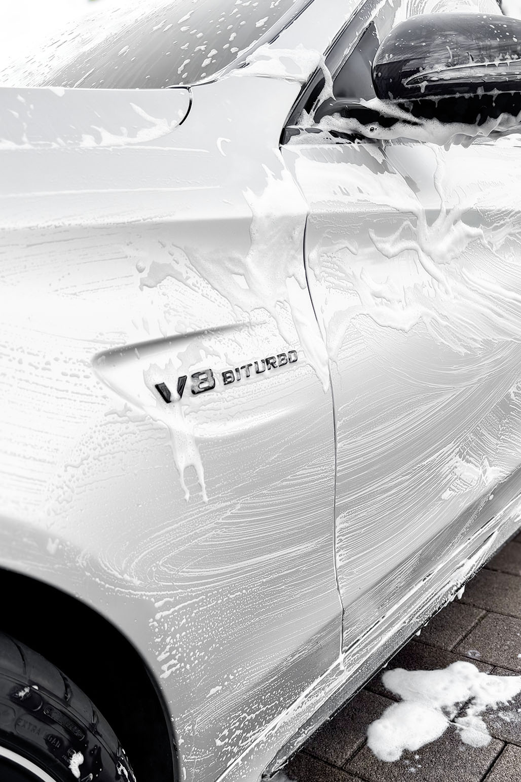 Weiße Schaumschicht auf V8 Biturbo Fahrzeug – intensive Lackwäsche mit Aktivschaum
