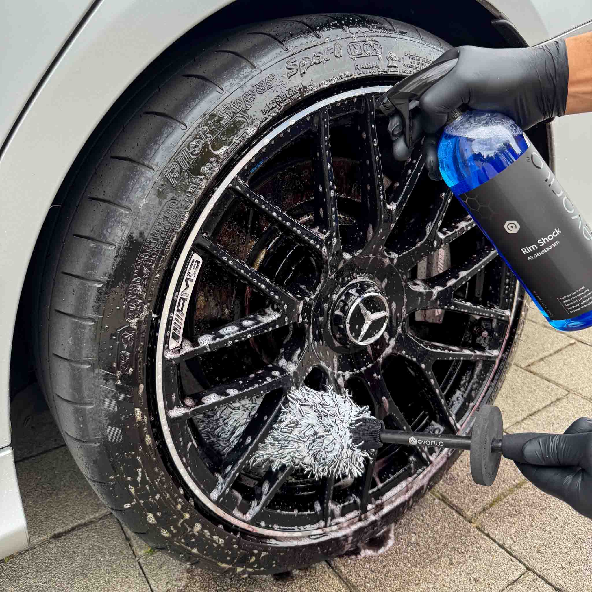 evorilo Deep Grip Felgenbürste reinigt schwarze Autoreifenfelge mit blauer Felgenreinigerflasche und Handschuhen
