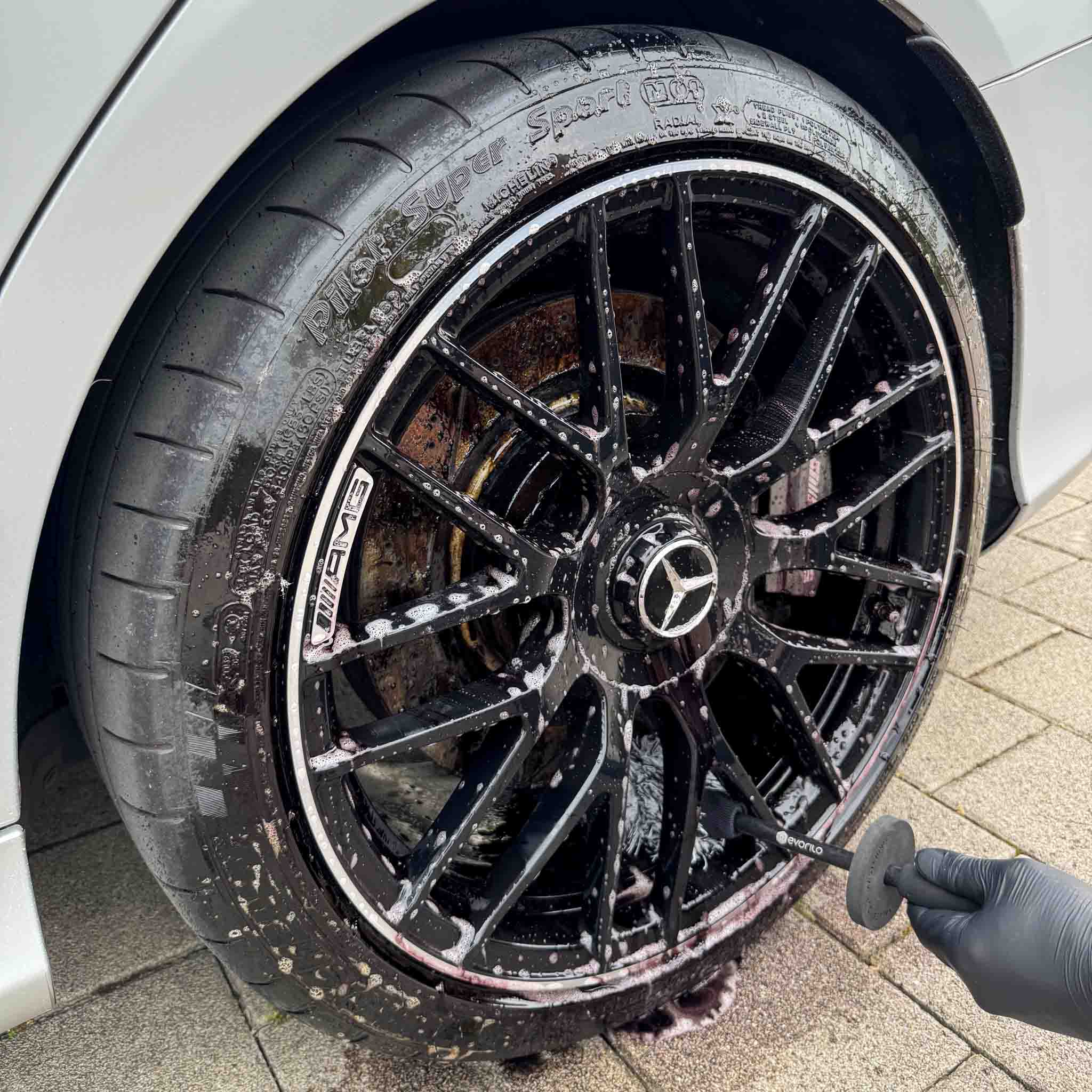 evorilo Deep Grip Felgenbürste reinigt schwarze Autoreifen effizient, Schaum sichtbar, Anwendung im Einsatz.