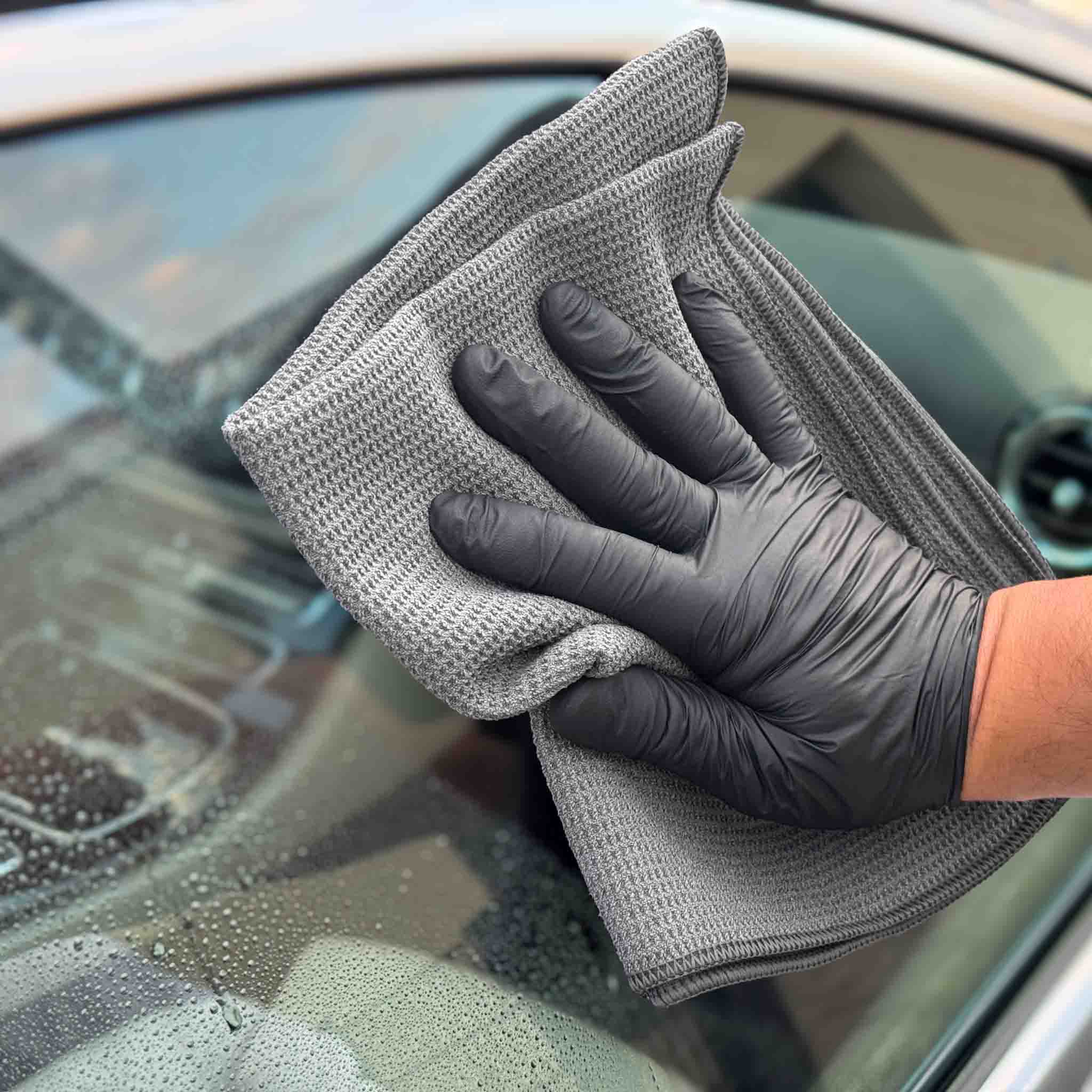 Hand mit schwarzem Handschuh reinigt Auto mit evorilo Hydro Waffle Glas Waffeltuch, ideal für klare Fenster.